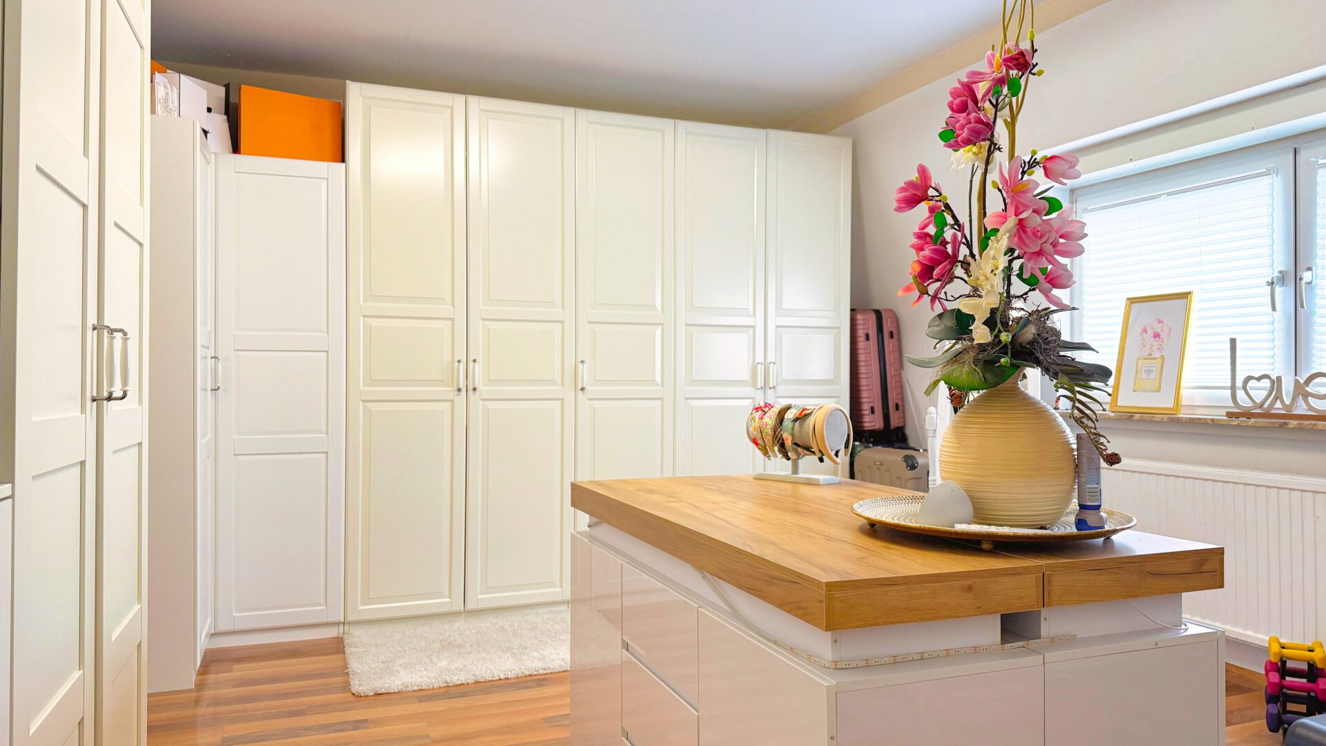 Ankleidezimmer mit großzügigen Einbauschränken und zentraler Kommode – optimal organisiert