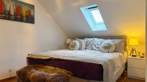 Gemütliches Schlafzimmer im Dachgeschoss mit Dachflächenfenster und stimmungsvoller Beleuchtung