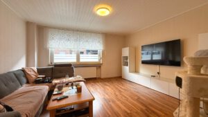 Helles Wohnzimmer mit großem Fenster, gemütlichem Sofa und modernem Medienbereich