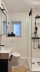 Modernes Gäste-WC mit ebenerdiger Dusche und stilvollen Fliesenakzenten (2)