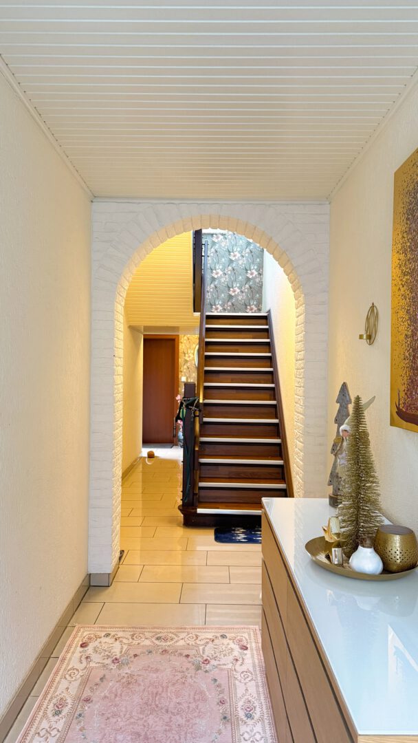 Einladender Eingangsbereich mit stilvollem Rundbogen und Massivholztreppe